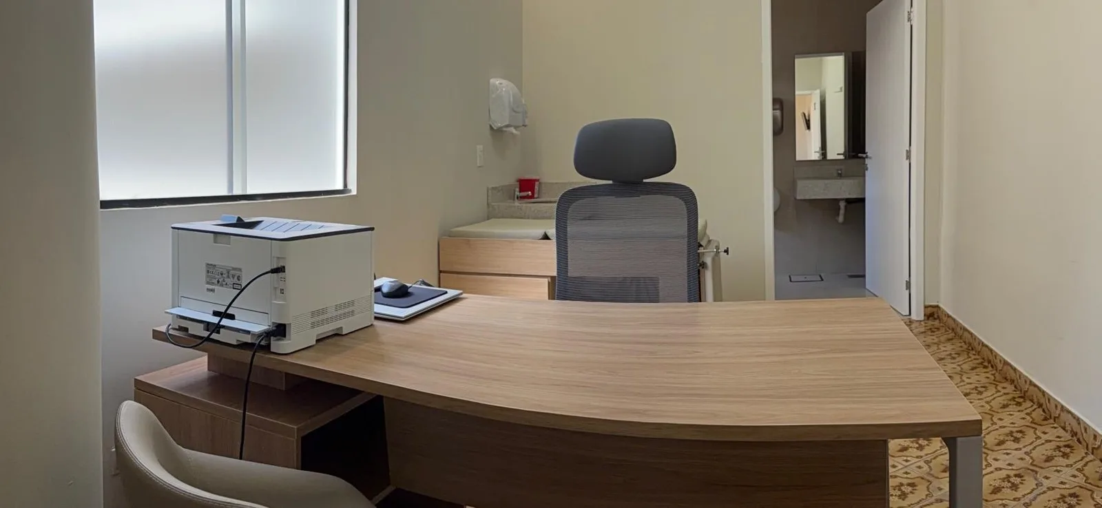 Consultorio de ginecología con escritorio y la puerta al baño propio
