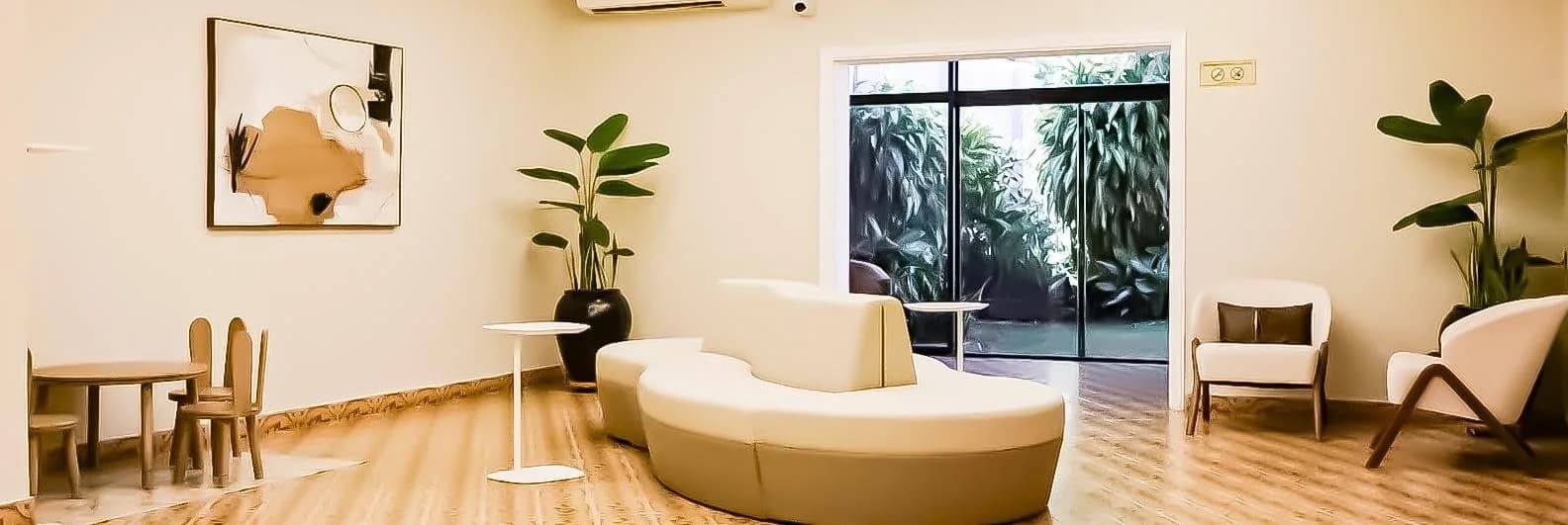 Sala de espera de CERTIVA con un sillón curvo, sillones individuales, plantas y una mesa infantil